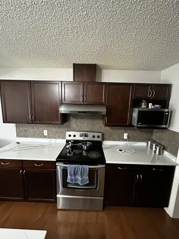 Kitchen cabinet refinishing by iPaint Painting — dark stained cabinets in Edmonton home